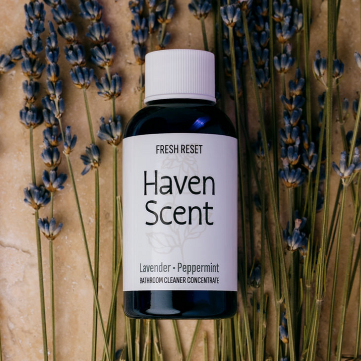 A bottle of Fresh Reset Haven Scent Lavender Peppermint bathroom cleaner concentrate, styled with dried lavender stems on a textured beige background.